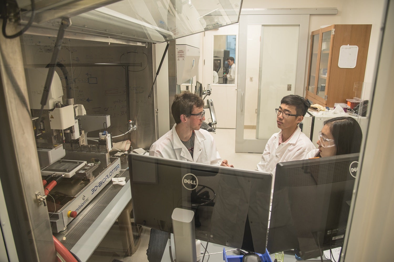Students discussing the use of a bioprinter